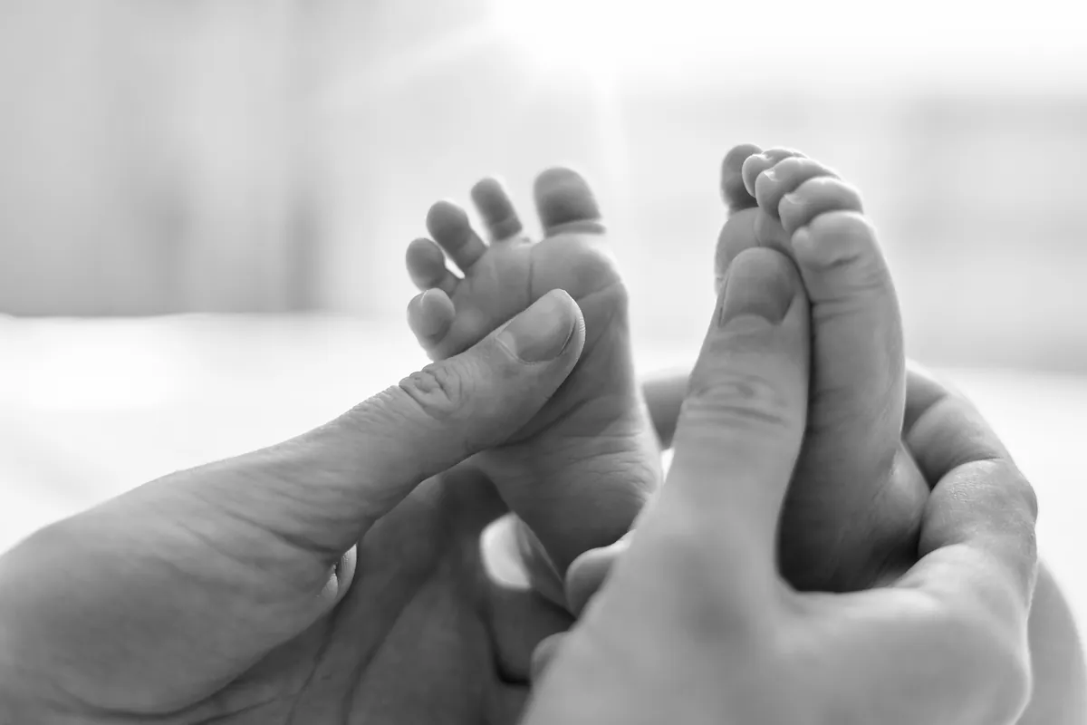 Massage métamorphique à Bellevue, pieds d'un nouveau-né tenus par les mains de sa maman