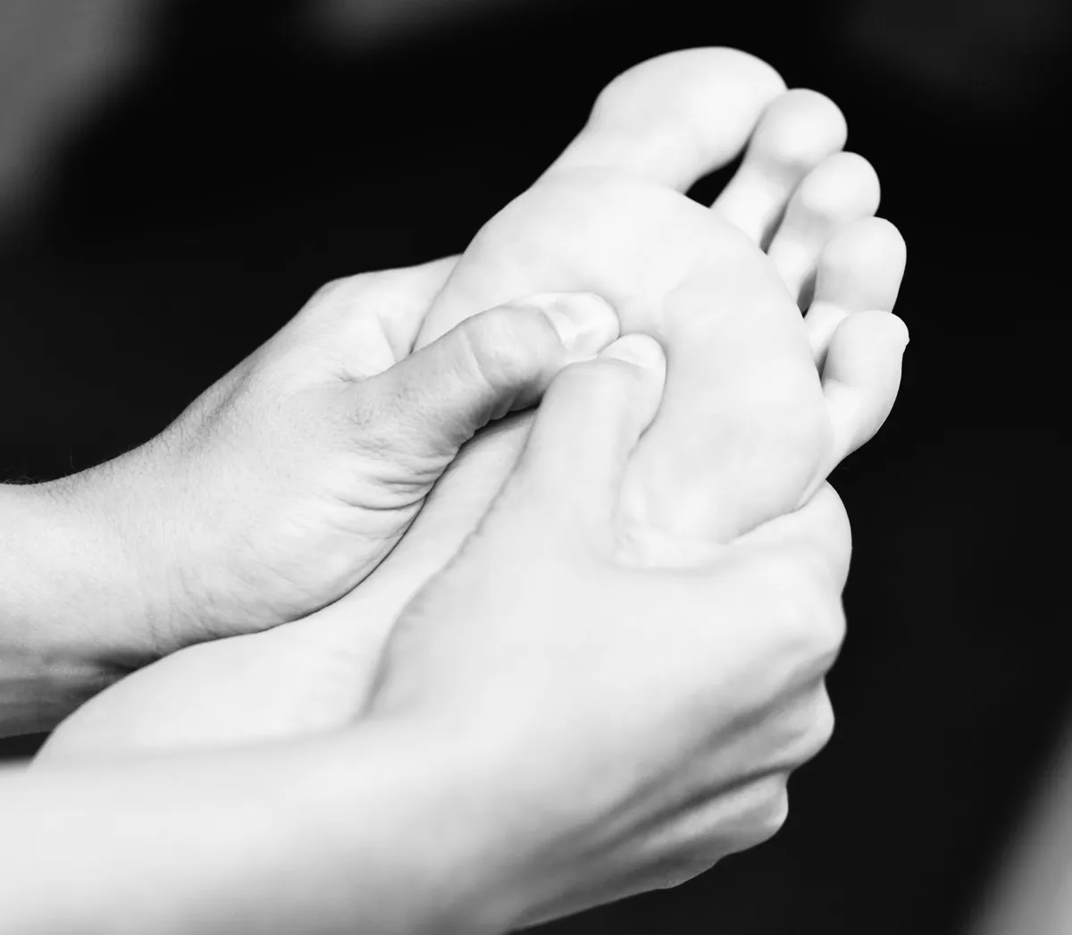 Séance de réflexologie plantaire pour adulte à Genève, mains stimulant les zones réflexes du pied